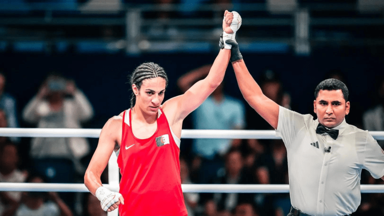 Algerian boxer Imane Khelif with her arm being raised in victory by a referee following a boxing match